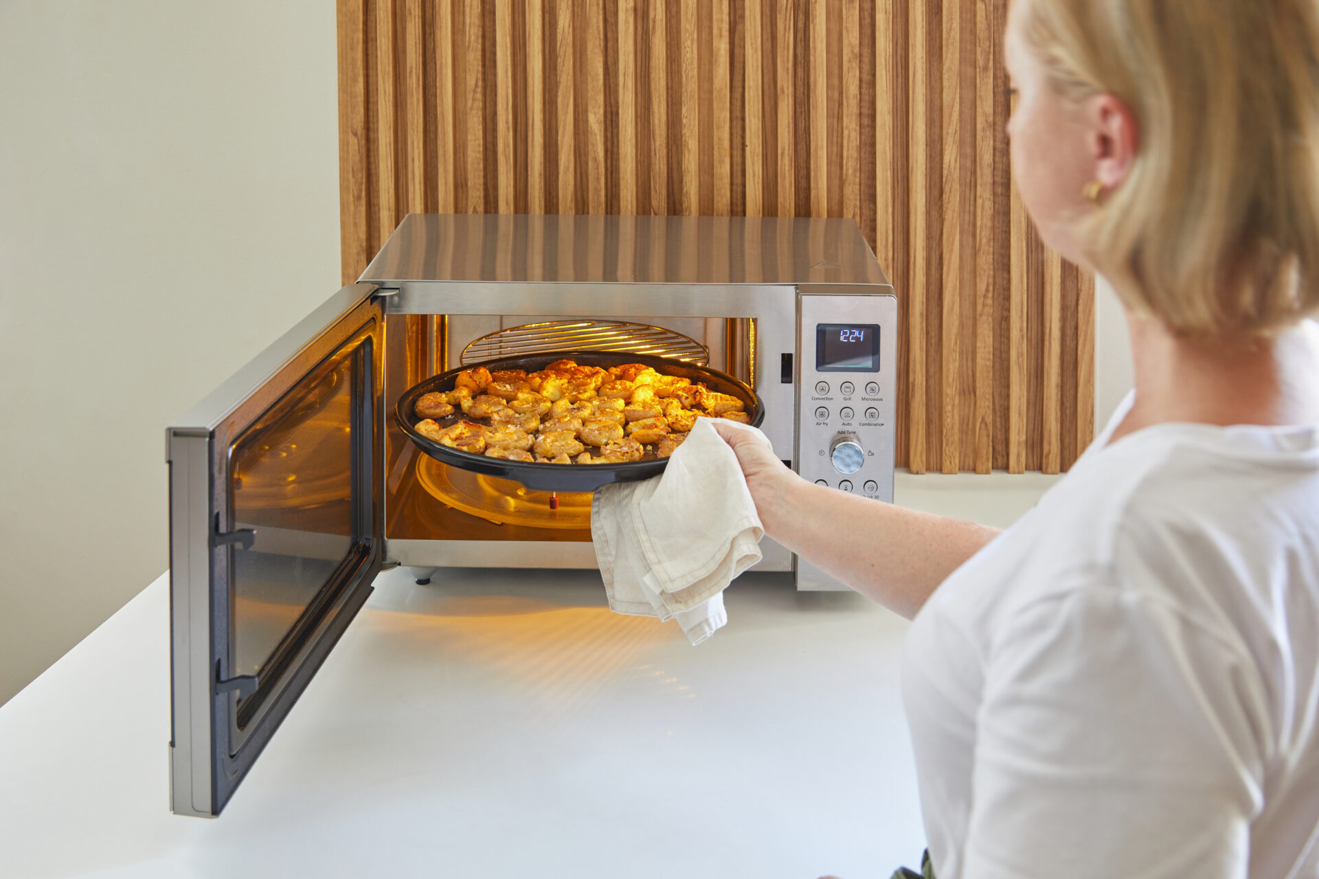 Panasonic NN-CT56RBEPG Panasonic NN-CT56RB kuchenka mikrofalowa Inverter Slim z grillem i funkcją Air Fry (1000 W, termoobieg, 27l, kosz do smażenia beztłuszczowego), czarna 41 Taca z potrawą wyjmowana z kuchenki Panasonic Slim Line Combi, ustawiona na ruszcie grillowym wewnątrz urządzenia.